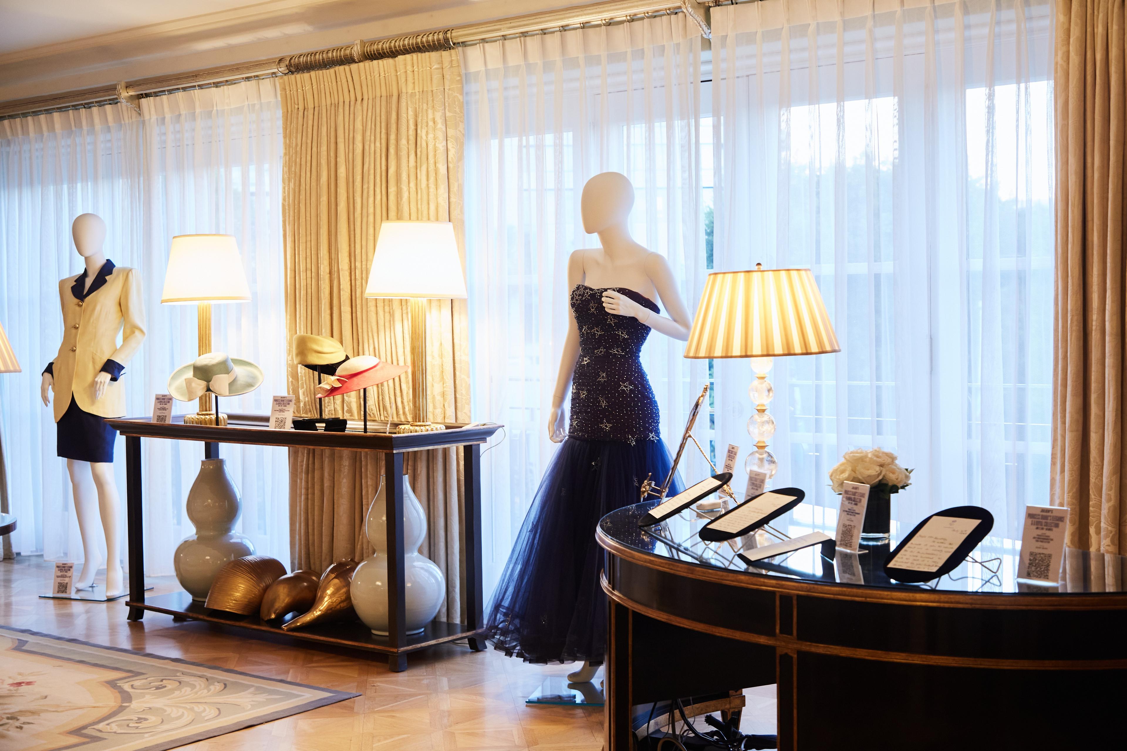 a room with a mannequin wearing a blue dress and a table with lamps .