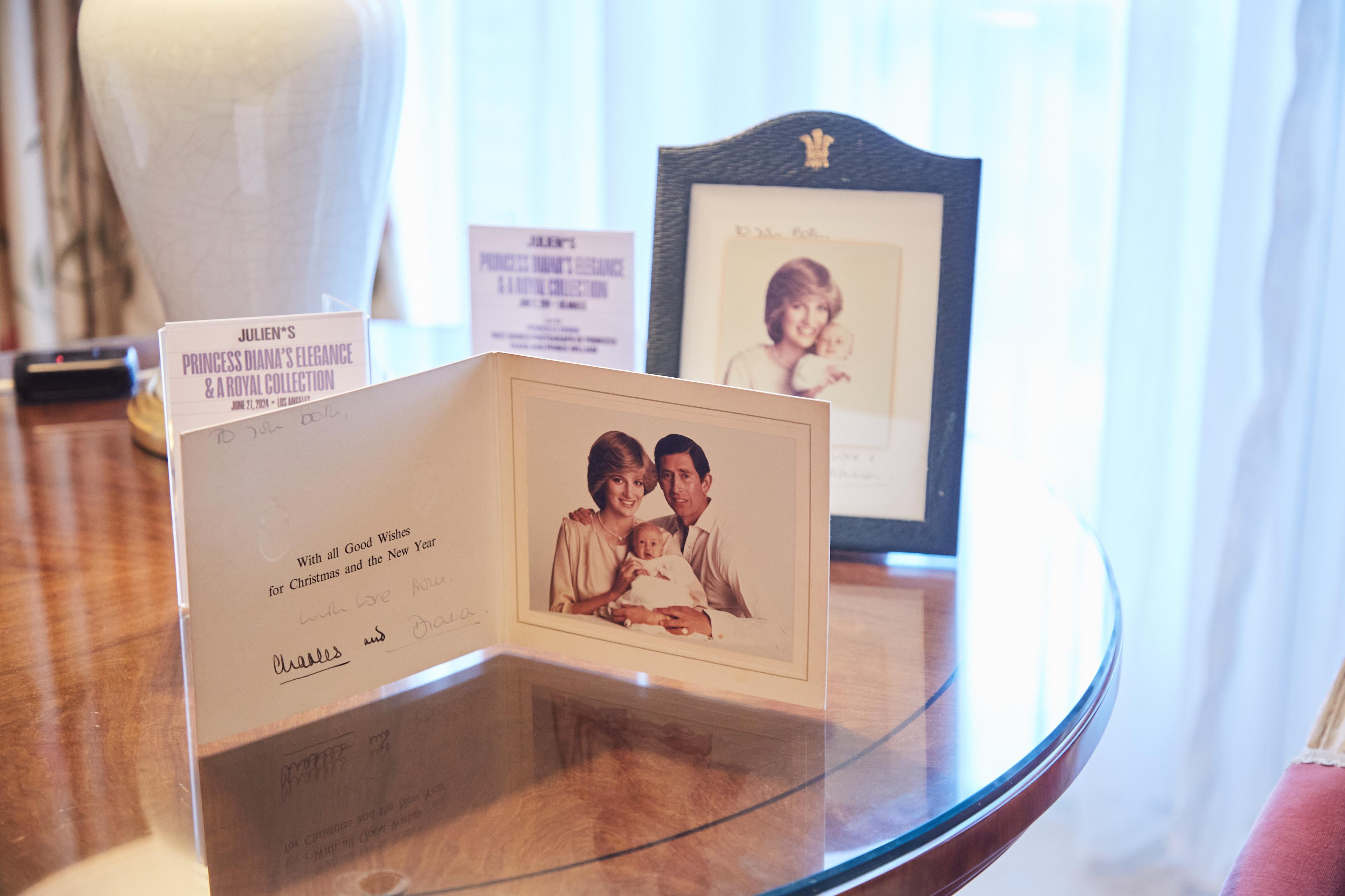 a christmas card with a picture of princess diana and prince charles is sitting on a glass table .