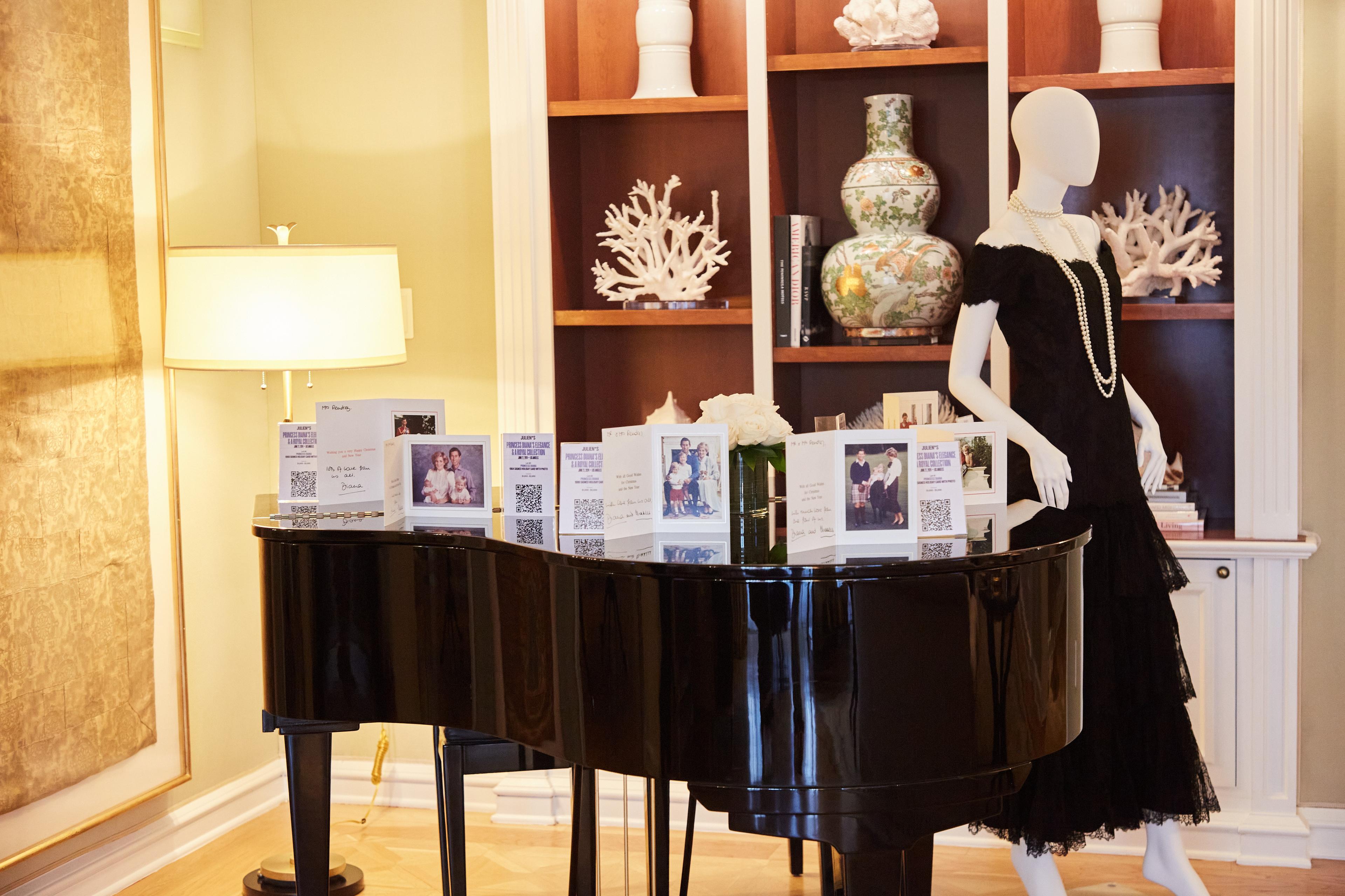 a mannequin in a black dress is standing in front of a piano .