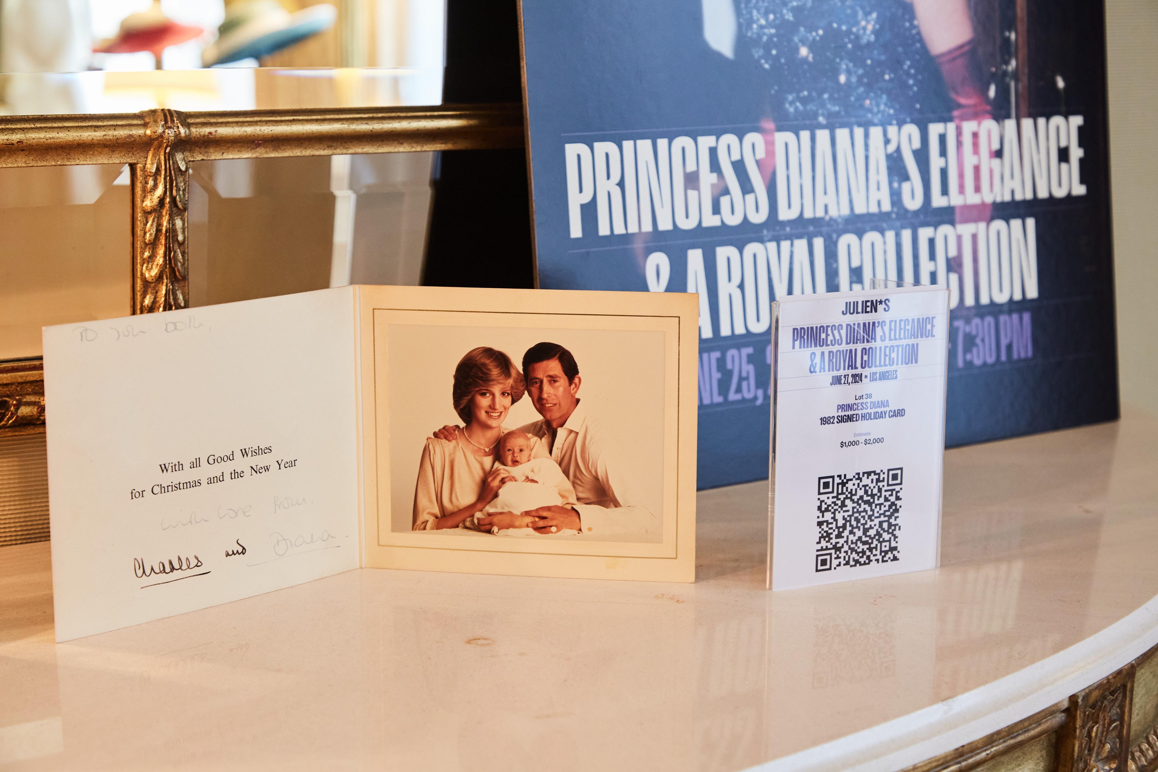 a christmas card and a picture of princess diana and prince charles are on a table .