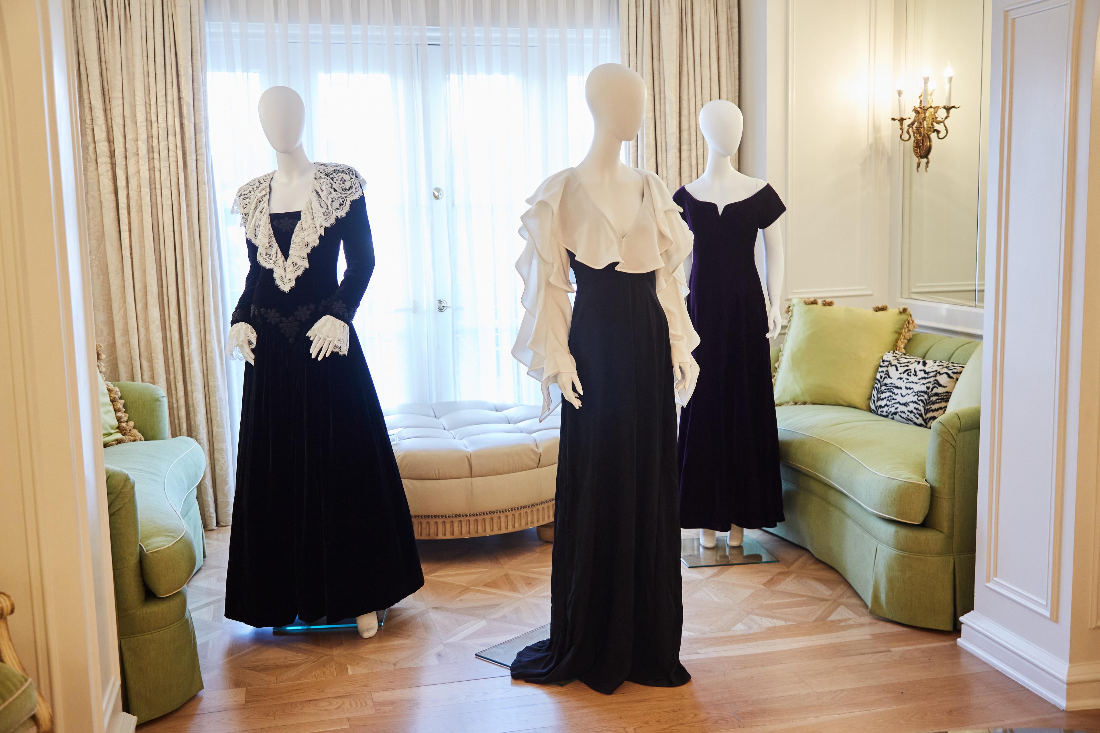three mannequins wearing black dresses are standing next to each other in a living room .